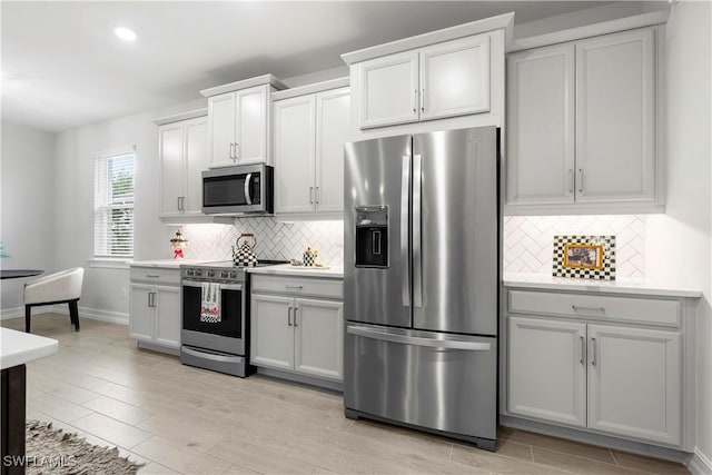 kitchen with light wood finished floors, white cabinetry, appliances with stainless steel finishes, and light countertops