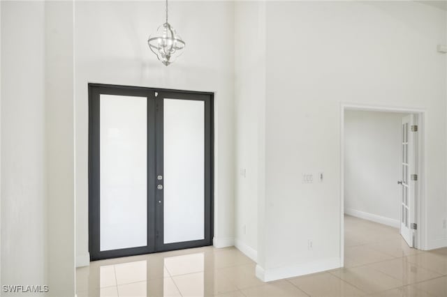 tiled foyer with a notable chandelier and french doors