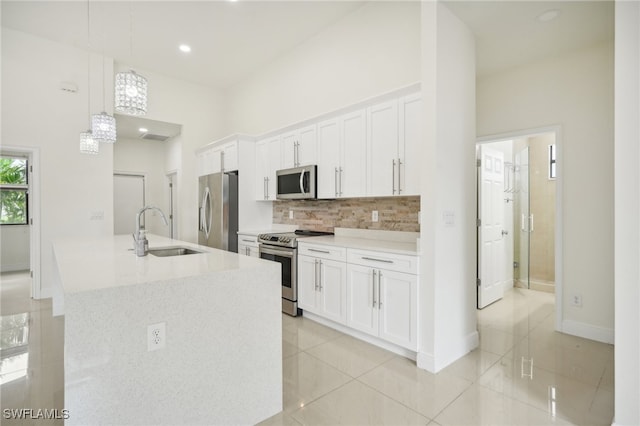 kitchen featuring light tile patterned floors, hanging light fixtures, appliances with stainless steel finishes, sink, and white cabinetry