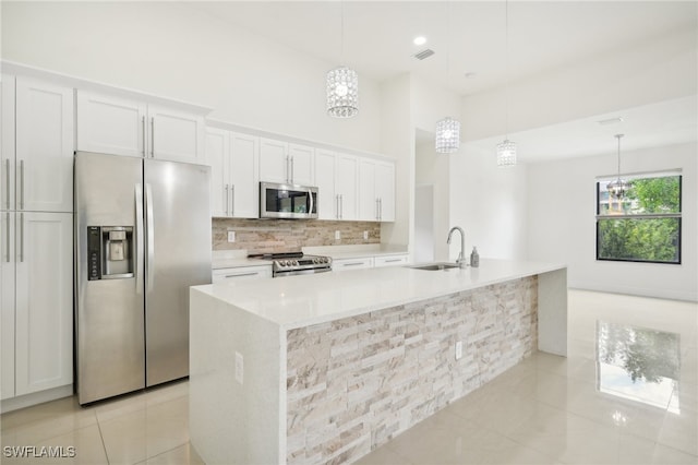 kitchen with light stone counters, white cabinetry, light tile patterned floors, decorative light fixtures, and stainless steel appliances