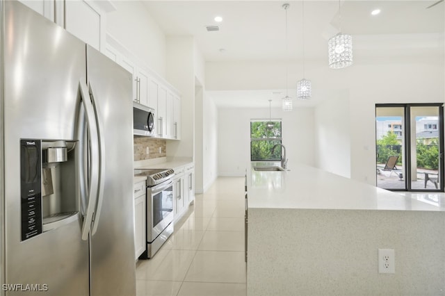 kitchen with light tile patterned flooring, stainless steel appliances, white cabinetry, sink, and decorative light fixtures