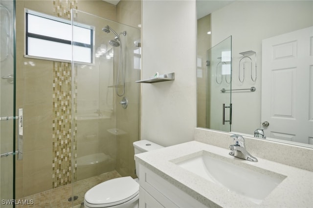 bathroom featuring a shower with door, toilet, and vanity