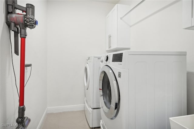 laundry room with washer and dryer, light tile patterned floors, and cabinets