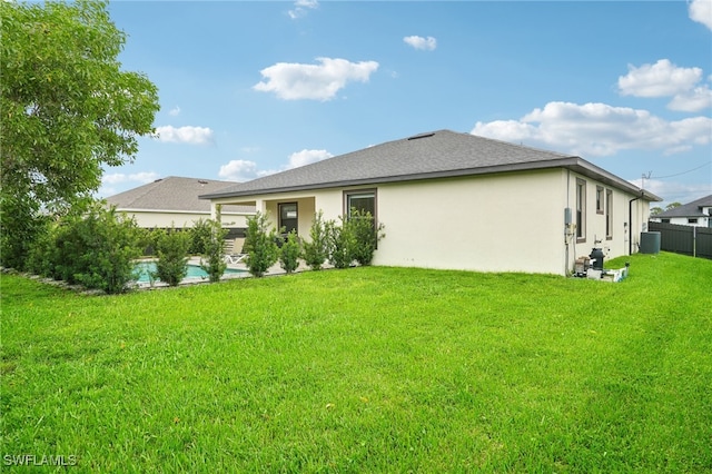 rear view of property featuring central air condition unit and a yard