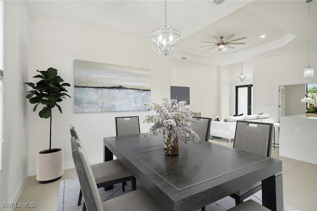 tiled dining room featuring a towering ceiling, ceiling fan with notable chandelier, and a tray ceiling