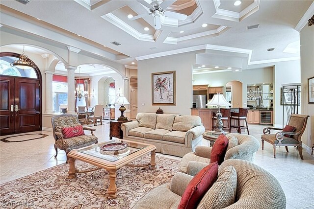 living room featuring light tile patterned flooring, crown molding, decorative columns, ceiling fan, and coffered ceiling