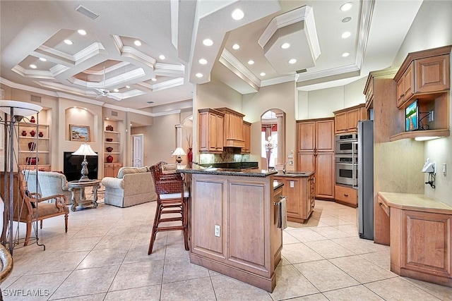 kitchen featuring coffered ceiling, a breakfast bar area, crown molding, a center island, and a towering ceiling