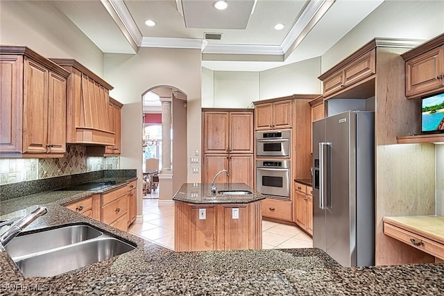 kitchen featuring sink, ornamental molding, stainless steel appliances, and a center island with sink