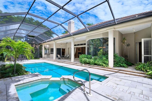 view of pool with a lanai, a patio, ceiling fan, and an in ground hot tub