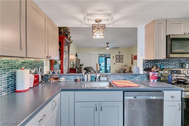 kitchen with kitchen peninsula, appliances with stainless steel finishes, backsplash, ceiling fan, and sink