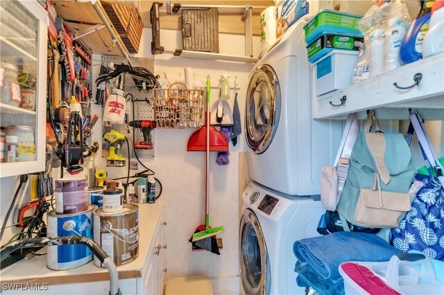 washroom featuring stacked washer / dryer and a workshop area