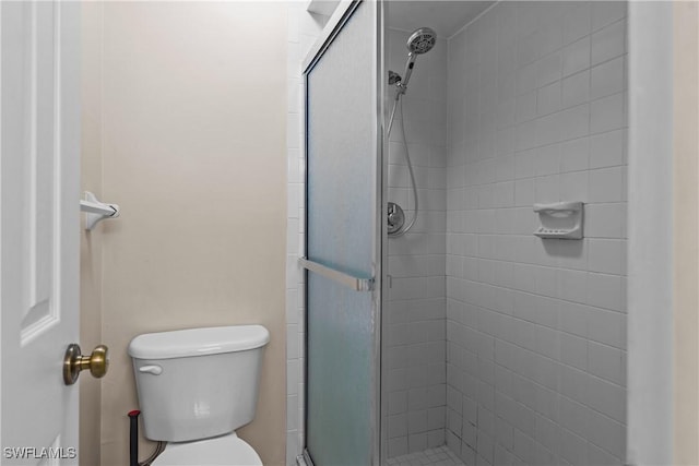 bathroom featuring a shower with shower door and toilet