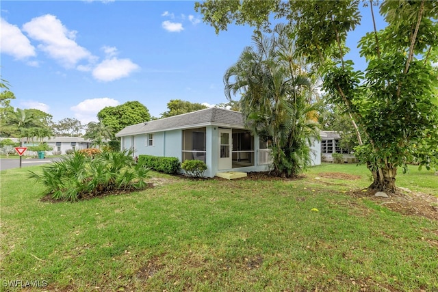 rear view of house with a lawn and a sunroom