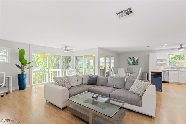 living room featuring light wood-type flooring, sink, and ceiling fan