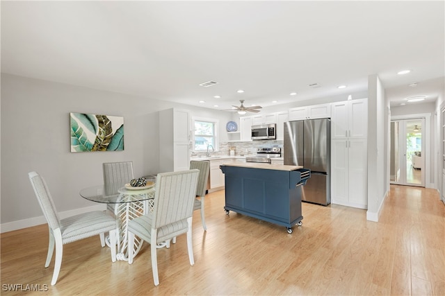 dining space featuring ceiling fan, light hardwood / wood-style floors, and sink