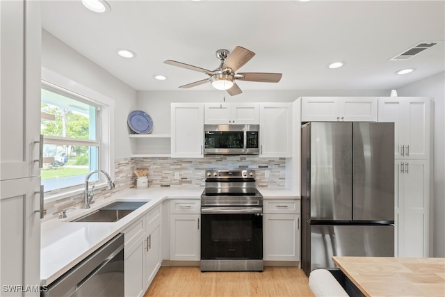 kitchen featuring white cabinetry, light hardwood / wood-style flooring, stainless steel appliances, sink, and ceiling fan