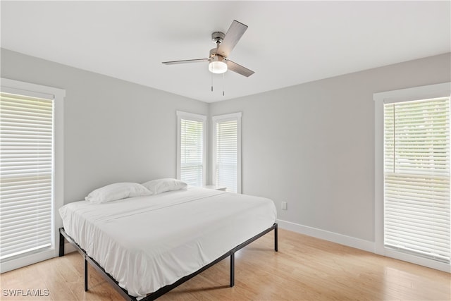 bedroom with light wood-type flooring, multiple windows, and ceiling fan