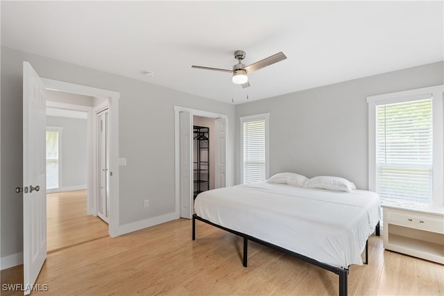 bedroom with light wood-type flooring, ceiling fan, and a closet