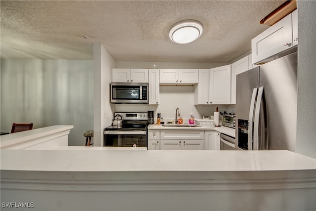 kitchen featuring white cabinetry, sink, stainless steel appliances, and a textured ceiling