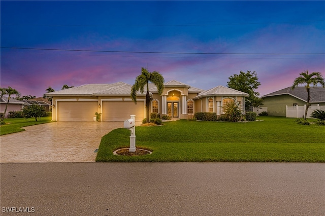 mediterranean / spanish house with a garage and a lawn