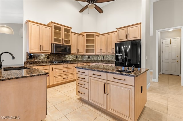 kitchen with sink, ceiling fan, stainless steel appliances, and a towering ceiling