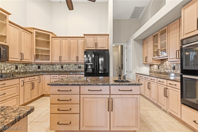 kitchen with light tile patterned floors, black appliances, and light brown cabinetry