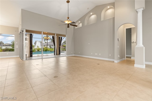 tiled empty room with decorative columns, a wealth of natural light, ceiling fan, and high vaulted ceiling