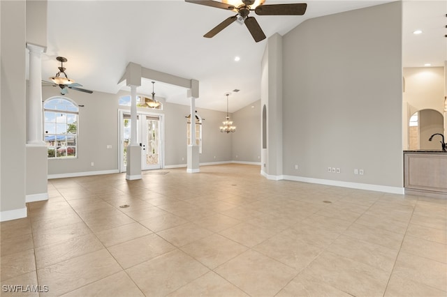 unfurnished living room with sink, light tile patterned flooring, ceiling fan with notable chandelier, and lofted ceiling