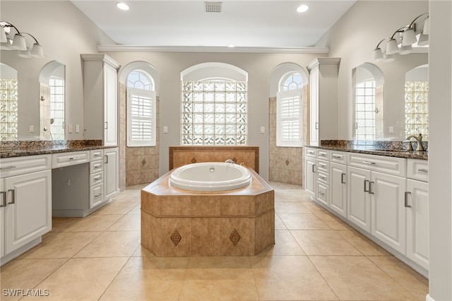 bathroom with tiled bath, tile patterned flooring, and double sink vanity