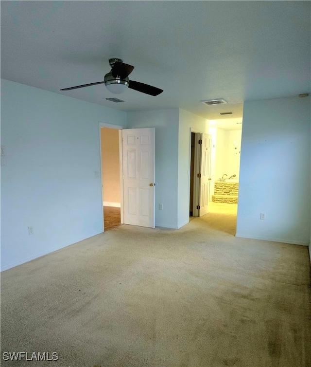 unfurnished bedroom featuring light carpet, ensuite bathroom, and ceiling fan