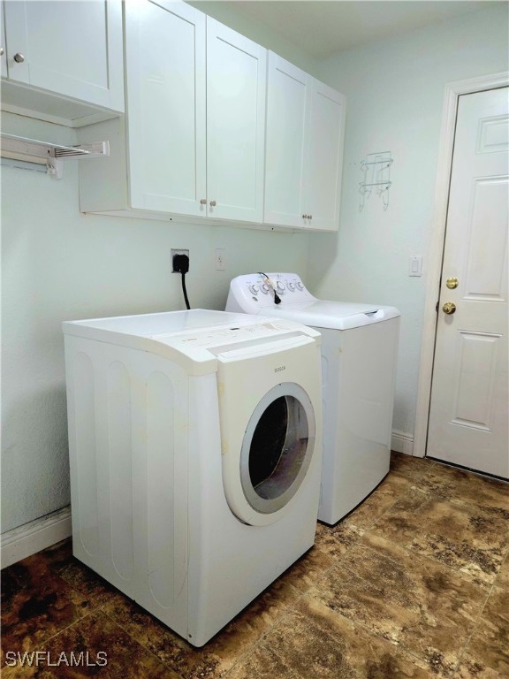 washroom with washer and clothes dryer, dark tile patterned flooring, and cabinets