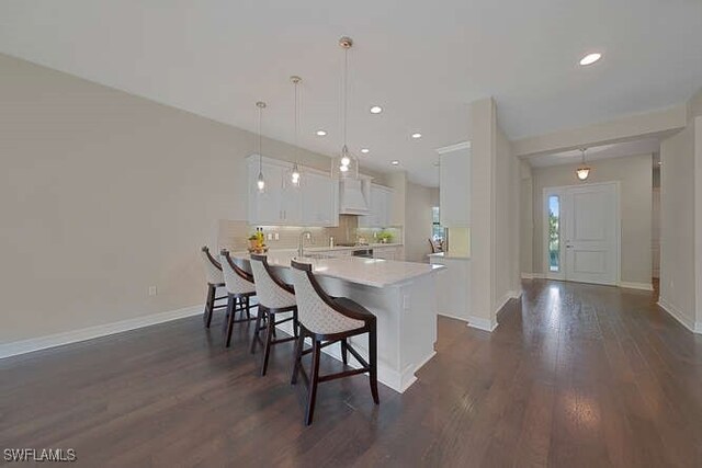 kitchen featuring kitchen peninsula, decorative light fixtures, dark hardwood / wood-style flooring, and white cabinets