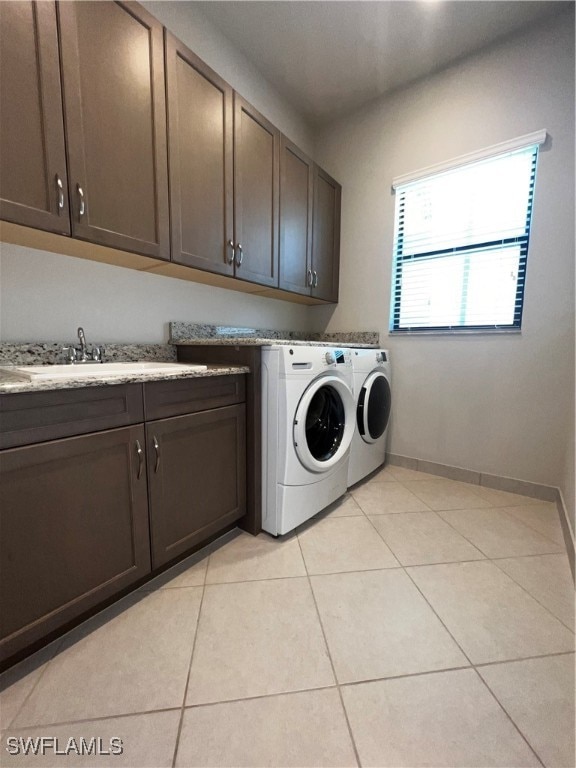 clothes washing area with sink, cabinets, washer and clothes dryer, and light tile patterned flooring