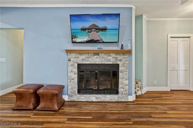 living room with a stone fireplace, crown molding, and hardwood / wood-style floors