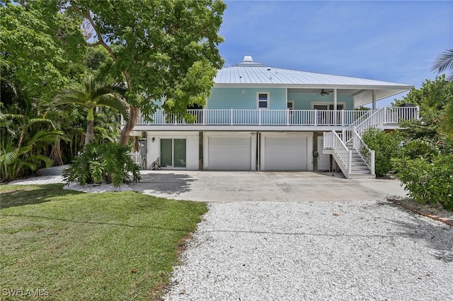 coastal inspired home with a porch, a garage, and a front lawn