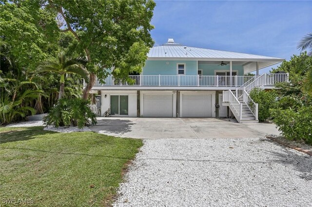 8335 Main St, Bokeelia, FL 33922 - coastal inspired home featuring stairway, a garage, metal roof, ceiling fan, and concrete driveway