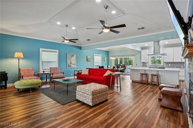 living room with vaulted ceiling, a stone fireplace, ceiling fan, wood-type flooring, and ornamental molding