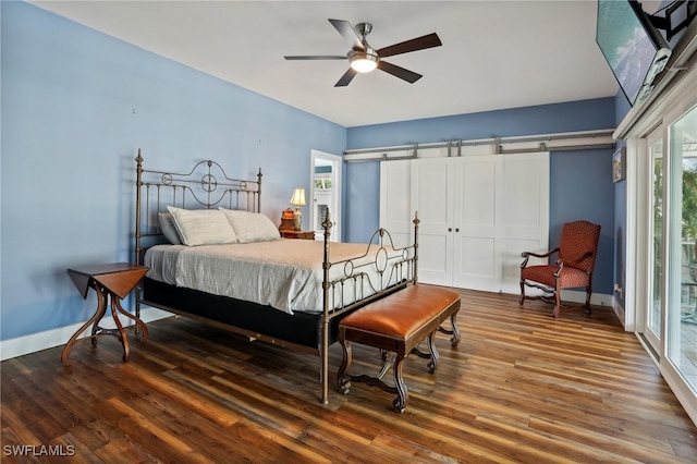 bedroom featuring access to outside, hardwood / wood-style floors, a barn door, and ceiling fan