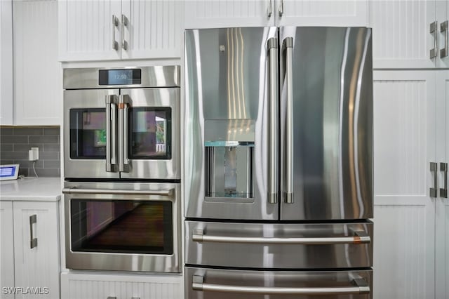 kitchen with white cabinets, backsplash, and stainless steel appliances