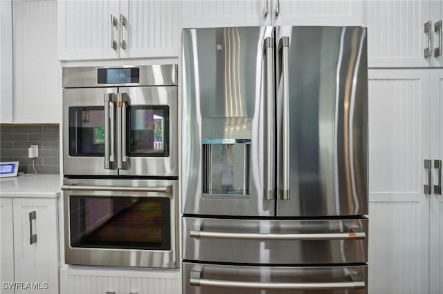 8335 Main St, Bokeelia, FL 33922 - kitchen with appliances with stainless steel finishes, white cabinetry, decorative backsplash, and light countertops