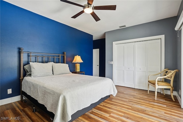 bedroom with a closet, hardwood / wood-style flooring, and ceiling fan