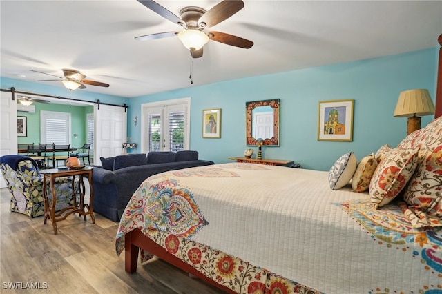 bedroom with light hardwood / wood-style floors, ceiling fan, and a barn door