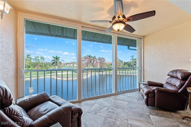 sunroom / solarium with ceiling fan and a water view