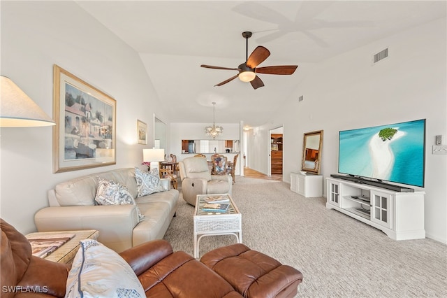 living room featuring ceiling fan with notable chandelier, light colored carpet, and vaulted ceiling