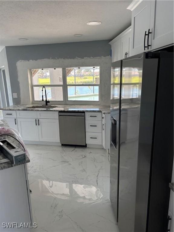 kitchen with white cabinetry, sink, light stone countertops, and appliances with stainless steel finishes