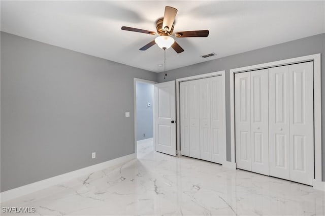 unfurnished bedroom featuring ceiling fan, visible vents, baseboards, multiple closets, and marble finish floor