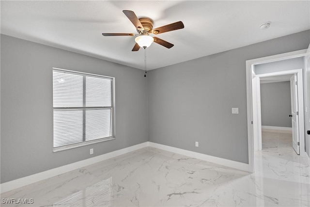 unfurnished room with marble finish floor, baseboards, and a ceiling fan