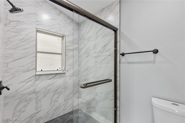 bathroom with toilet and a marble finish shower