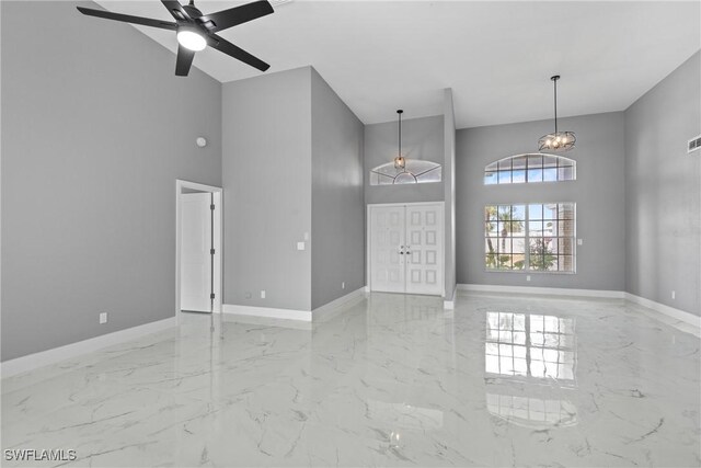 unfurnished room with marble finish floor, visible vents, a high ceiling, and baseboards