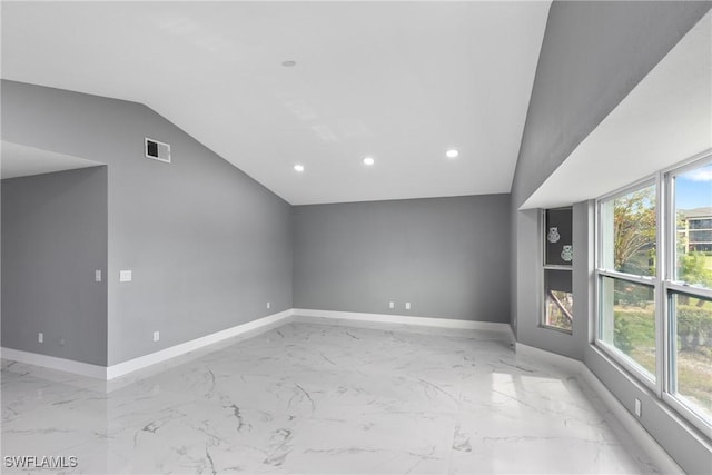 spare room with lofted ceiling, marble finish floor, visible vents, and baseboards